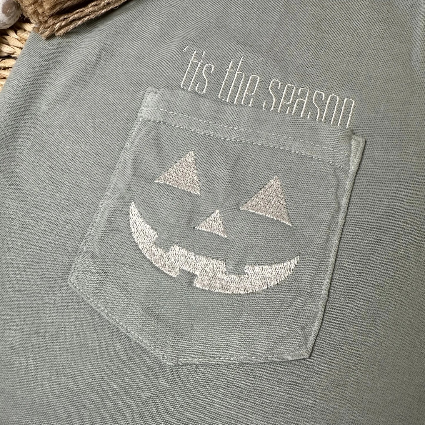 Comfort Colors pocket tee with embroidered Tis the Season text above pocket and jack-o’-lantern face on pocket