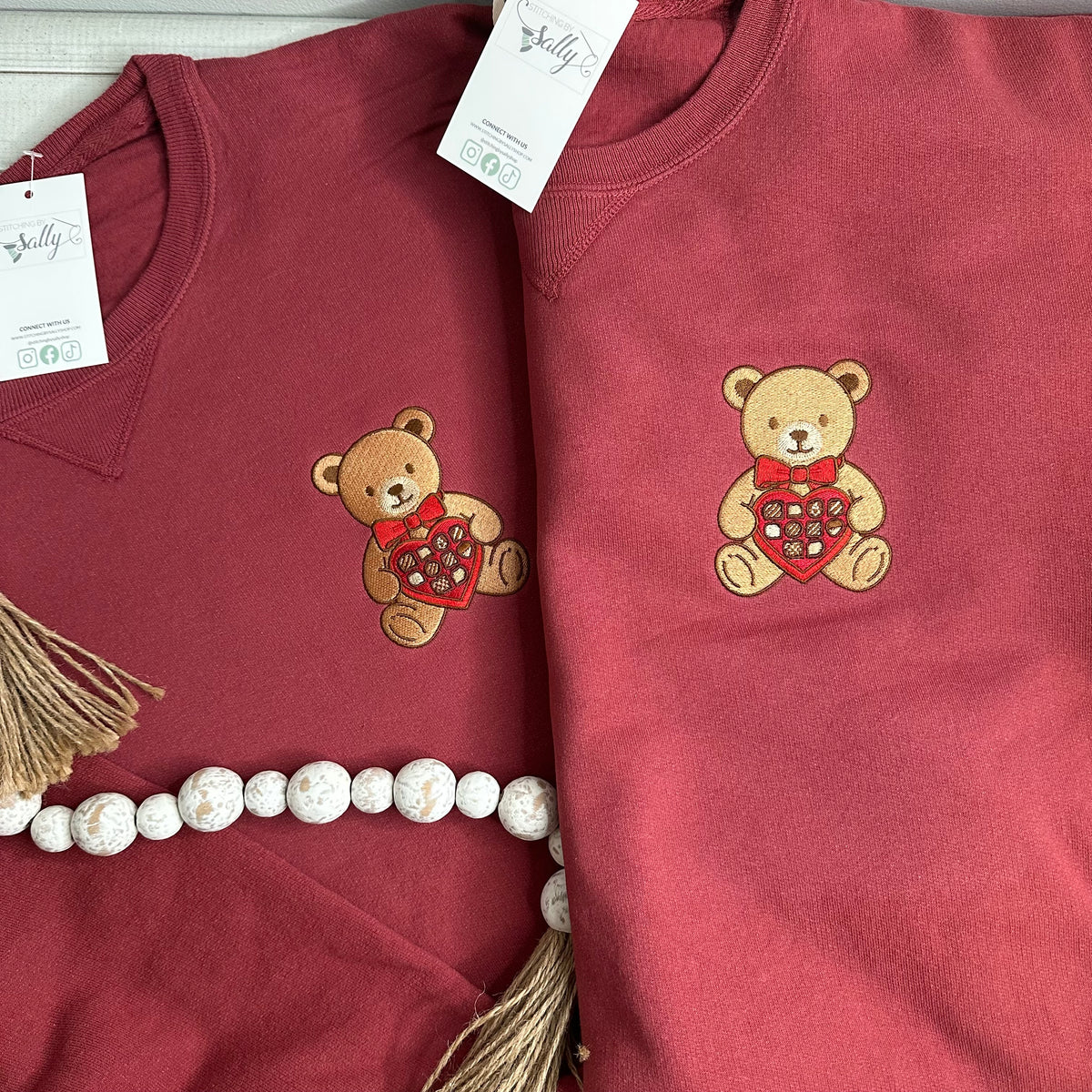 A bear with a box of chocolates embroidered onto a sweatshirt