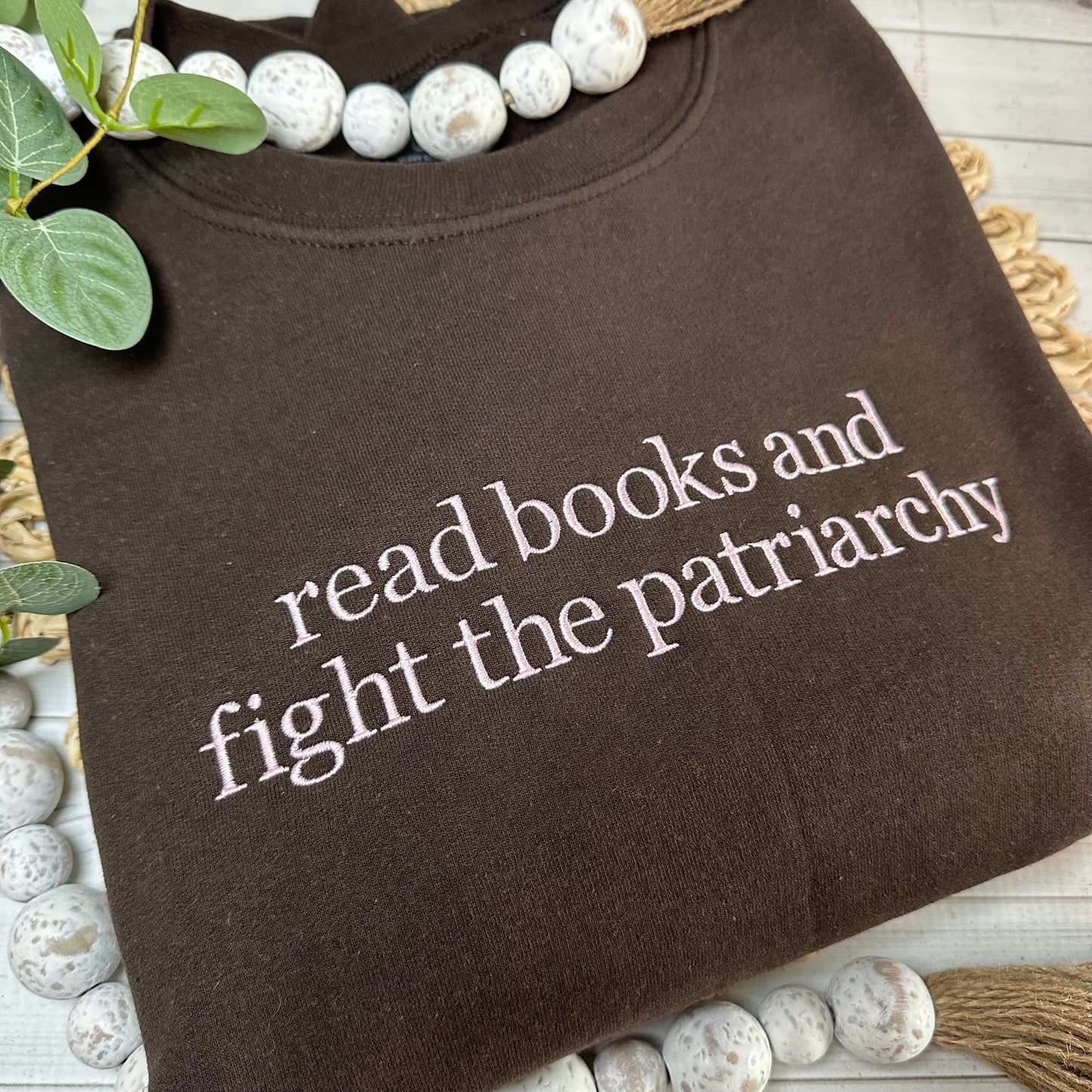 Close up of brown sweatshirt with light pink thread embroidery - feminist