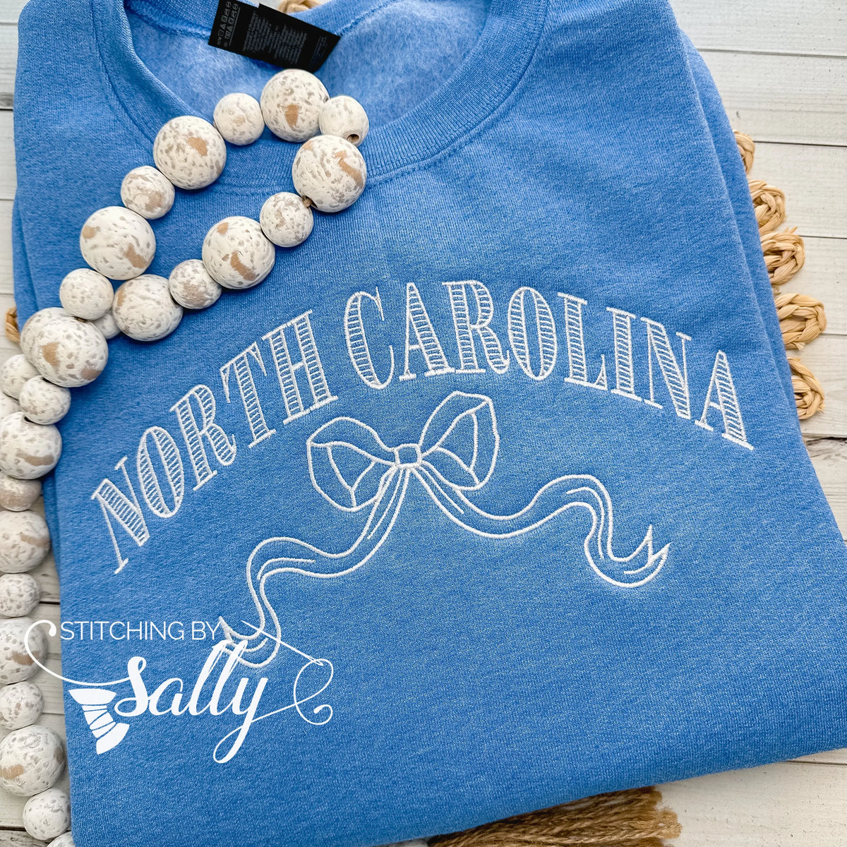 Striped North Carolina embroidered sweatshirt with a coquette bow, available in custom sweatshirt and thread colors. This one is blue