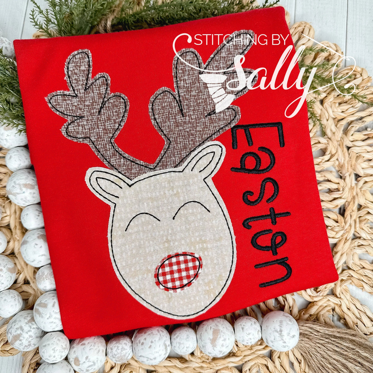 A folded red shirt with brown reindeer appliqué with a red nose.