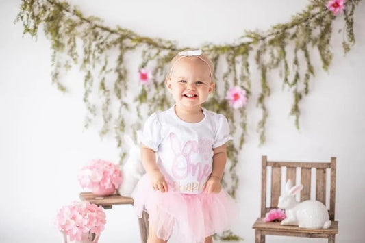 Child wearing some bunny is one birthday shirt with a pink tutu.