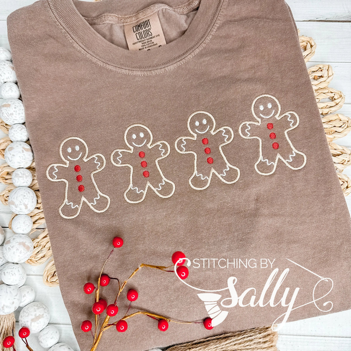 A brown shirt with four Gingerbread men embroidered in tan thread with red buttons.