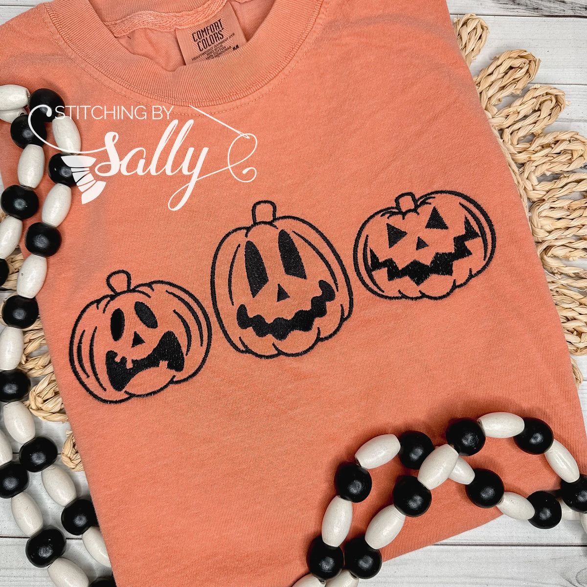 Jack o lanterns embroidered in black thread on an orange comfort colors shirt.