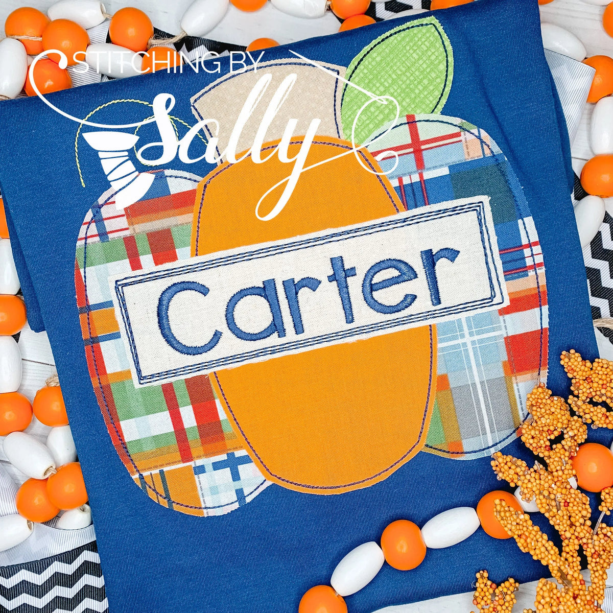 Front view of boys' navy shirt with orange and plaid pumpkin appliqué