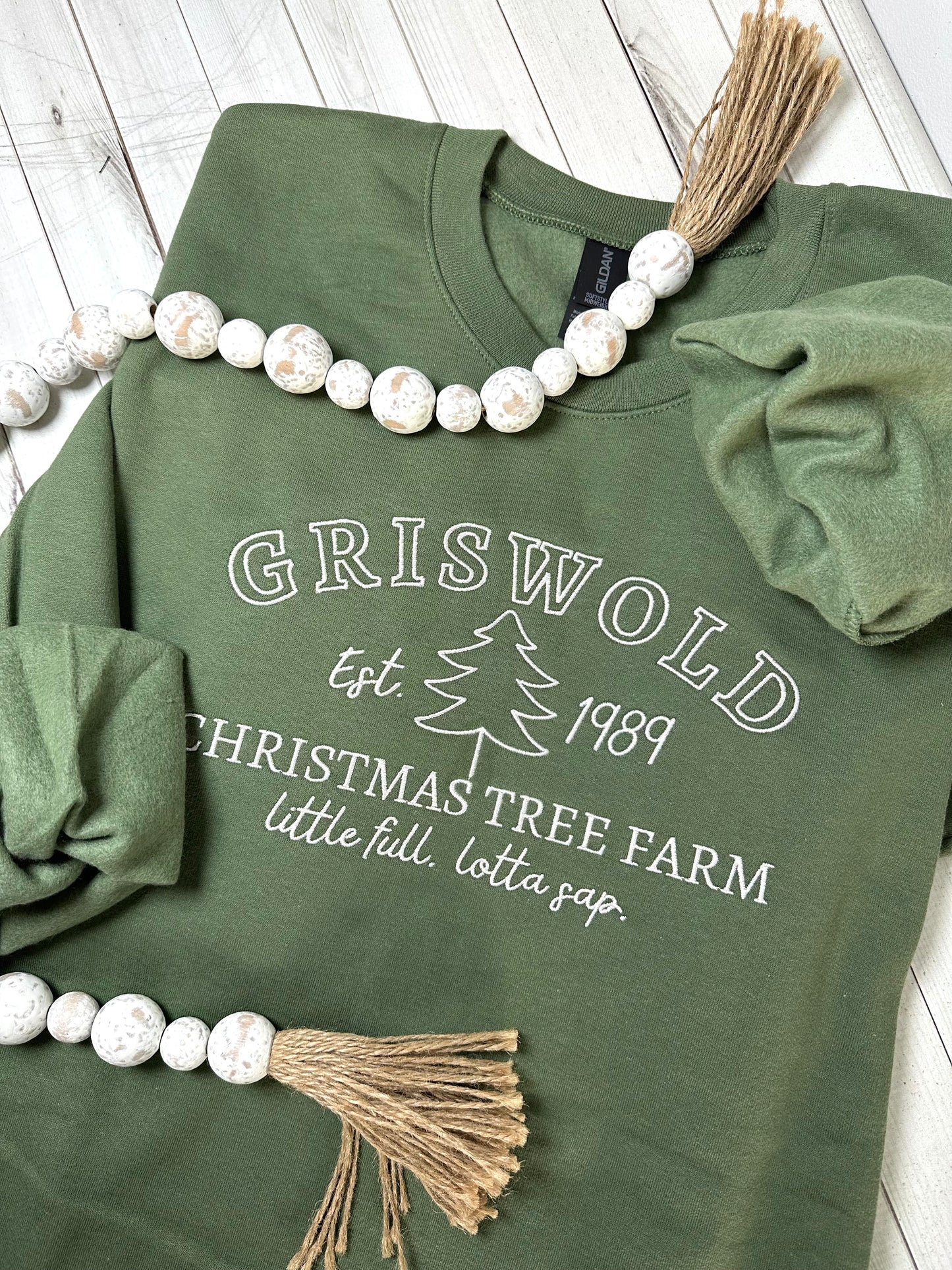 An army green sweatshirt with griswold Christmas tree farm embroidered on the front.