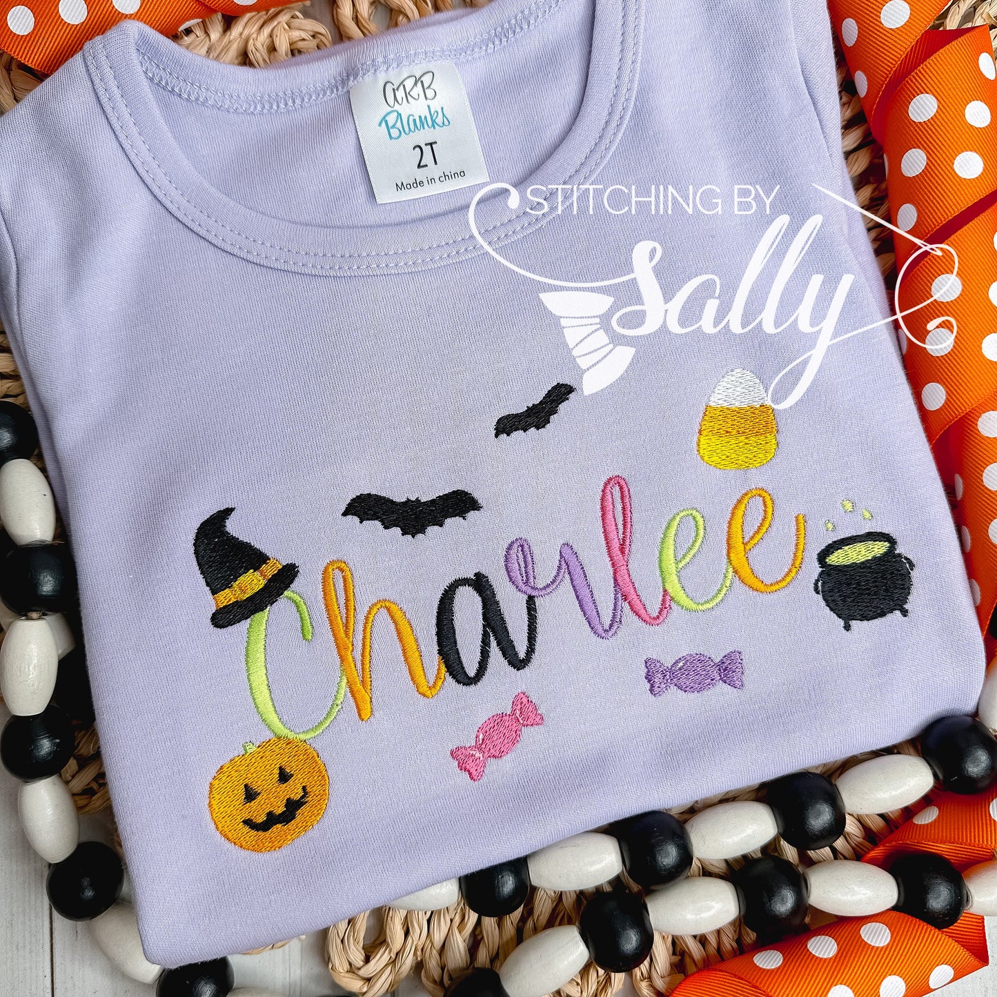 Front view of lilac Halloween shirt with embroidered name and spooky icons
