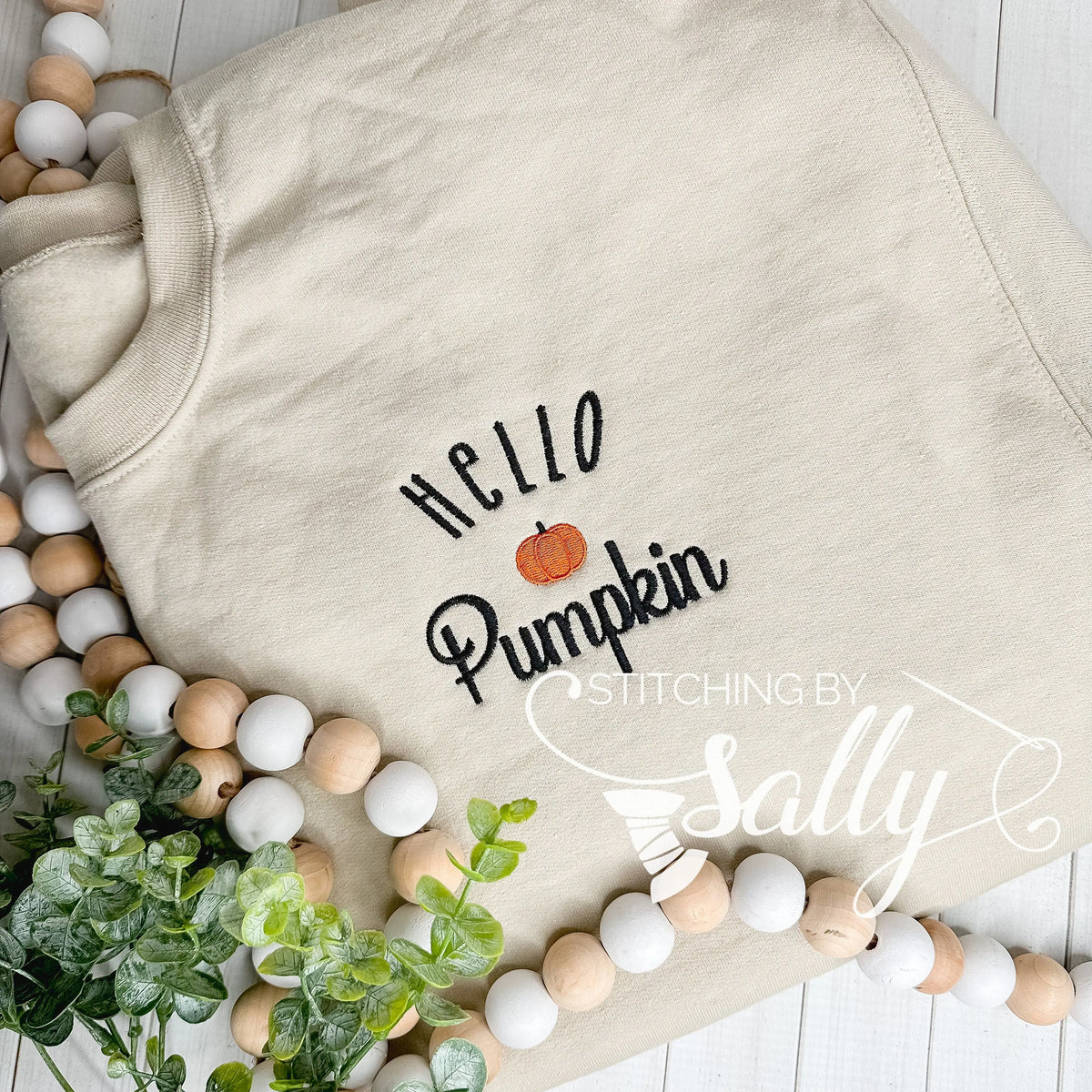 Sand Gildan sweatshirt with Hello Pumpkin embroidery in black thread with an orange pumpkin.