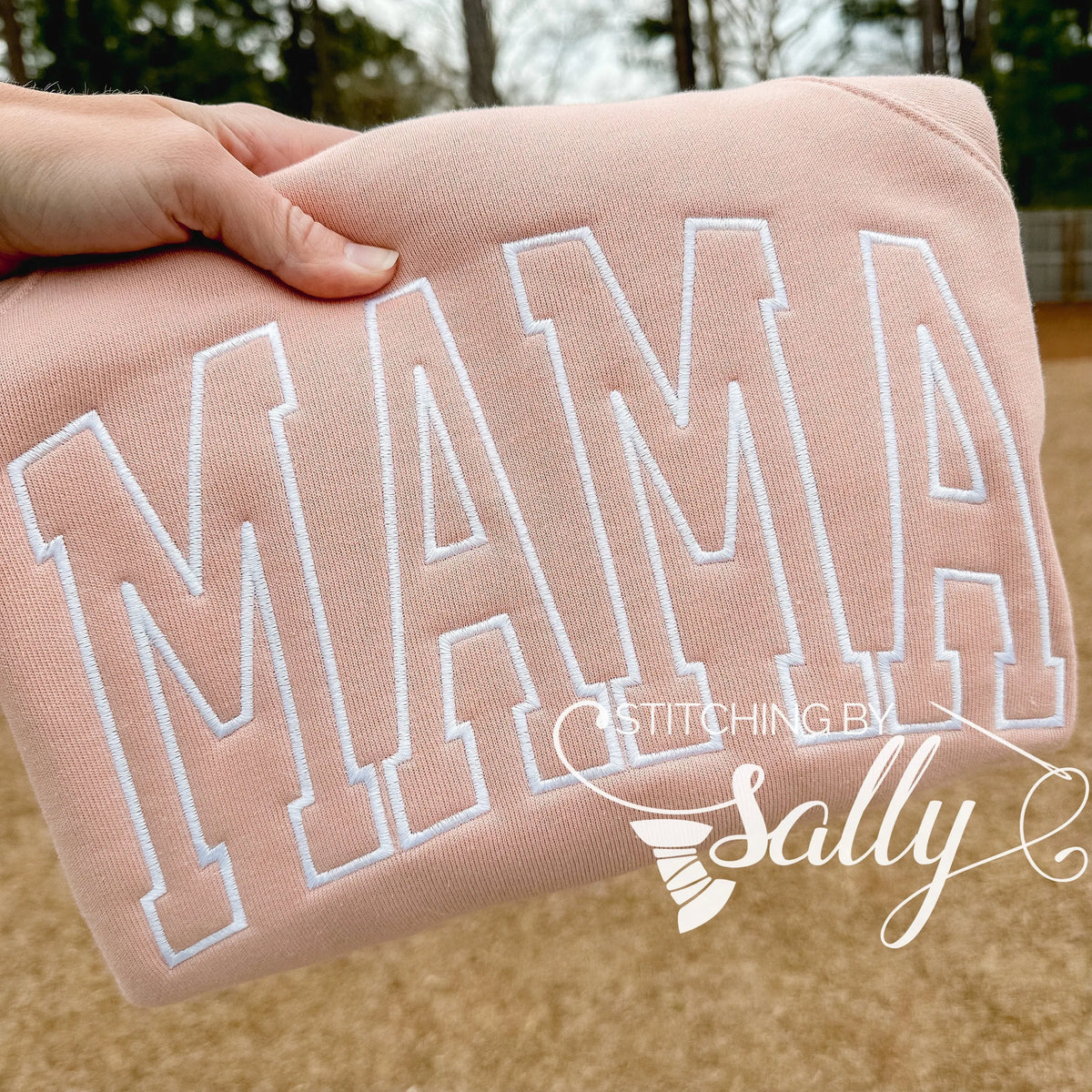 MAMA embroidered in white thread on a peach colored sweatshirt.