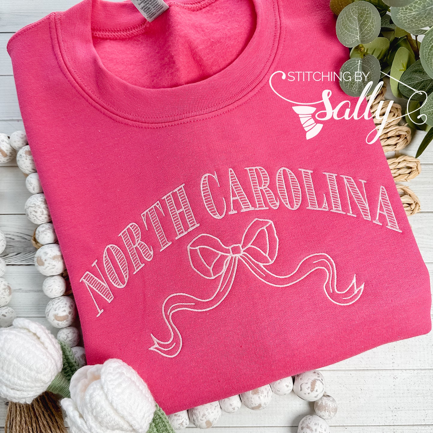 Striped North Carolina embroidered sweatshirt with a coquette bow, available in custom sweatshirt and thread colors. This one is pink.