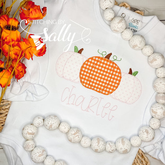 Front view of girls' white ruffle shirt with pumpkin trio appliqué