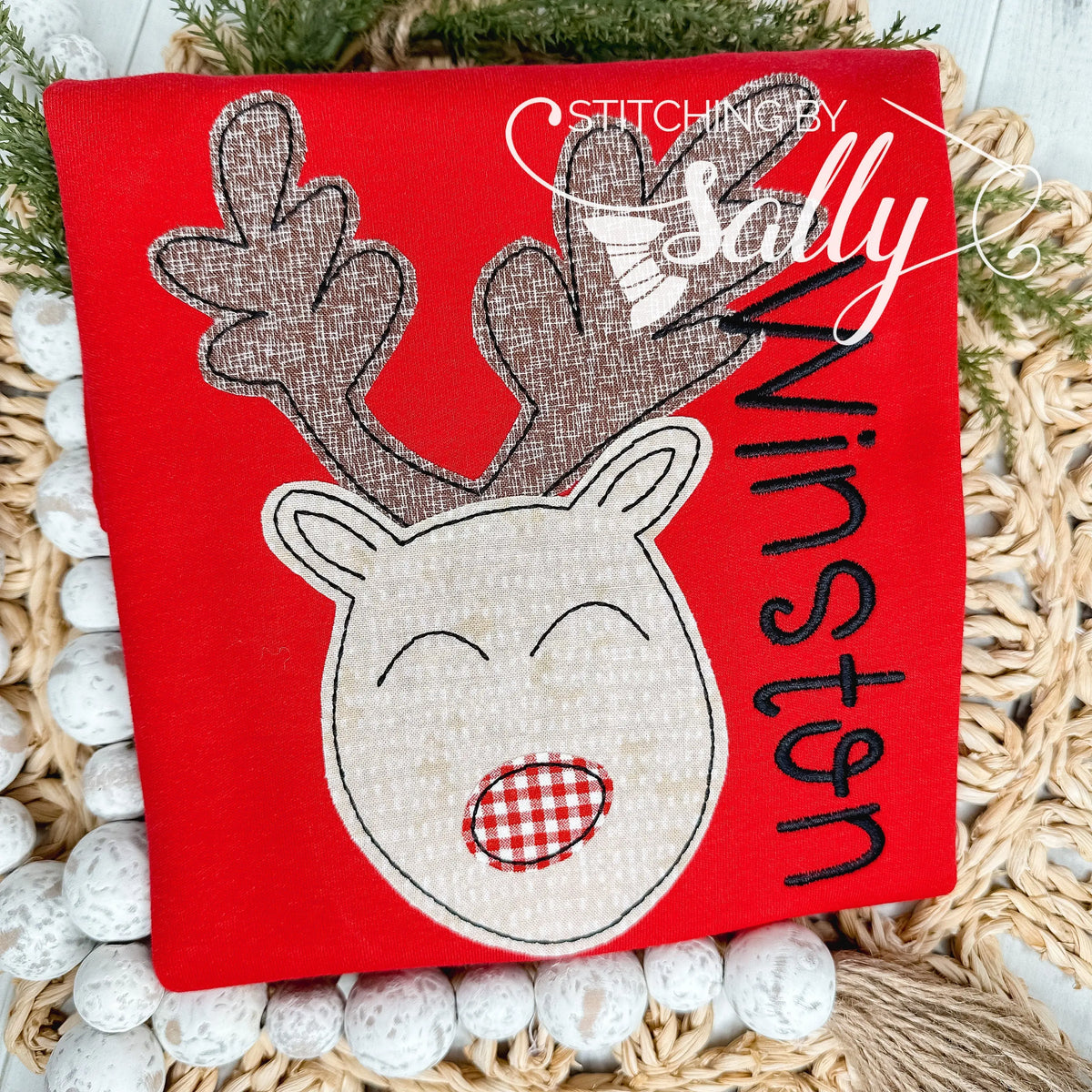 A red shirt with a brown reindeer applique with a red nose.