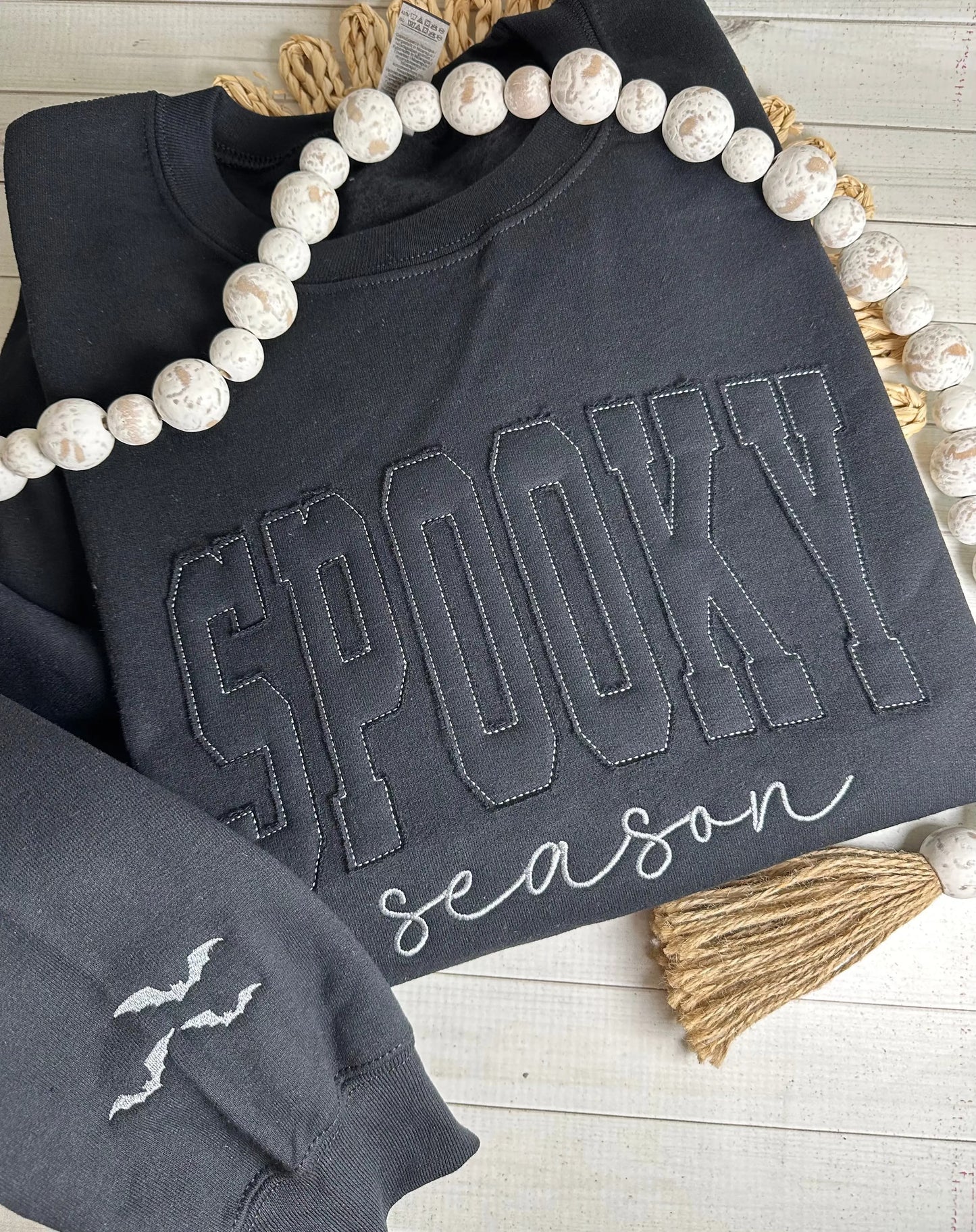 Black sweatshirt with 'Spooky Season' text appliquéd on. Bats embroidered on sleeve.