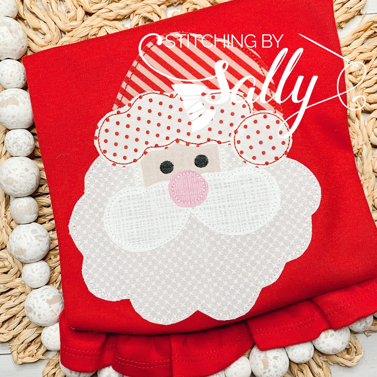 A girls red shirt with a santa face applique in red and white fabric. Personalized with name in black thread.