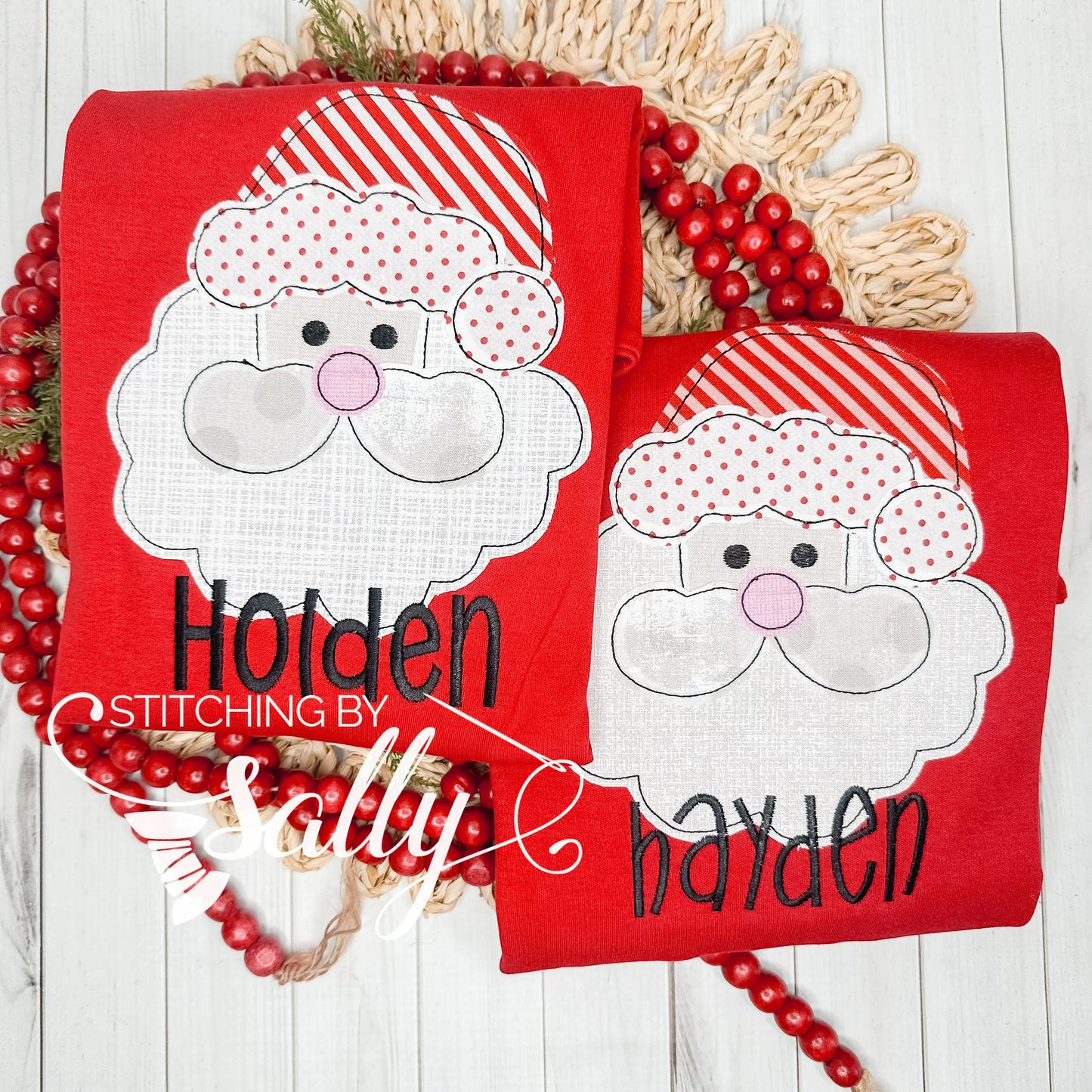 Two red folded shirts with Santa faces and embroidered names.