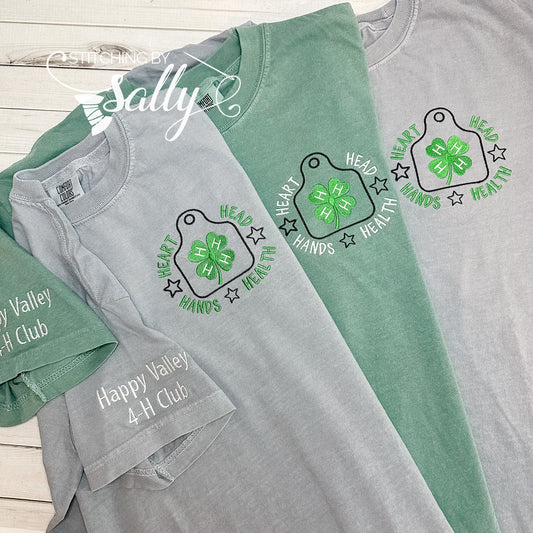 Close up of the 4-H motto embroidered on the left chest of a shirt with a green 4 leaf clover. Personalize with your club name on the sleeve. 