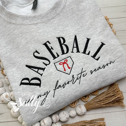A grey sweatshirt with the words “baseball is my favorite season” embroidered on it with a cute red bow. Colors can be customized to match your favorite team!