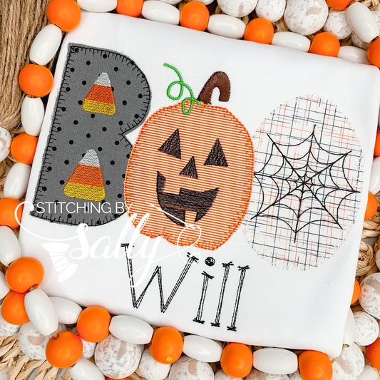 A white shirt with a Halloween-themed applique design including a pumpkin, candy corn, and spider web.