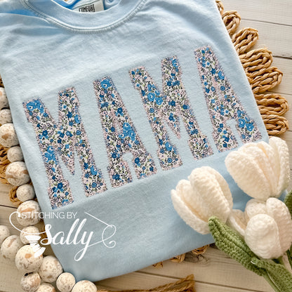Light blue Comfort Colors shirt featuring 'Mama' appliqué in a beautiful blue and pink floral fabric, finished with a delicate diamond stitch in light pink thread for a soft, elegant touch. Perfect for mothers day.