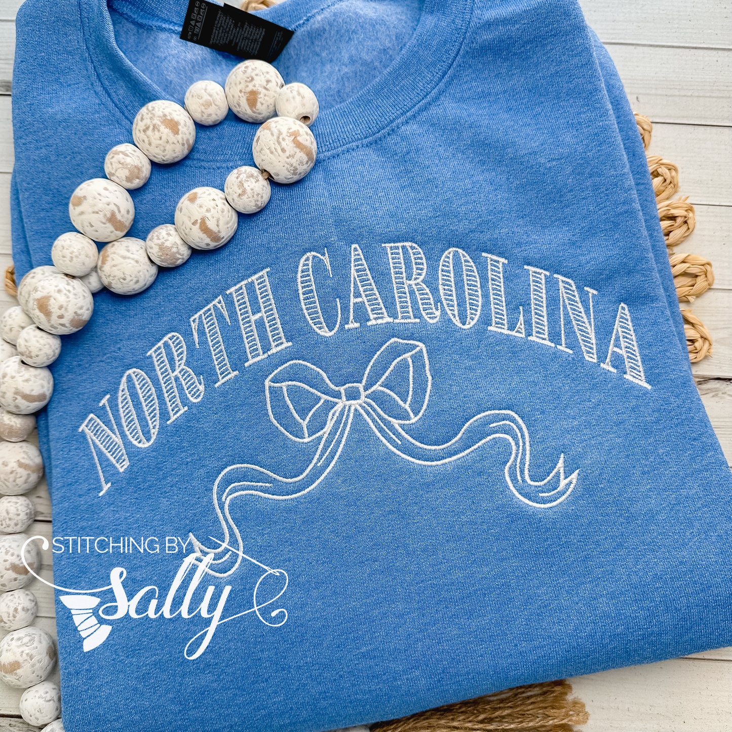 Striped North Carolina embroidered sweatshirt with a coquette bow, available in custom sweatshirt and thread colors. This one is blue