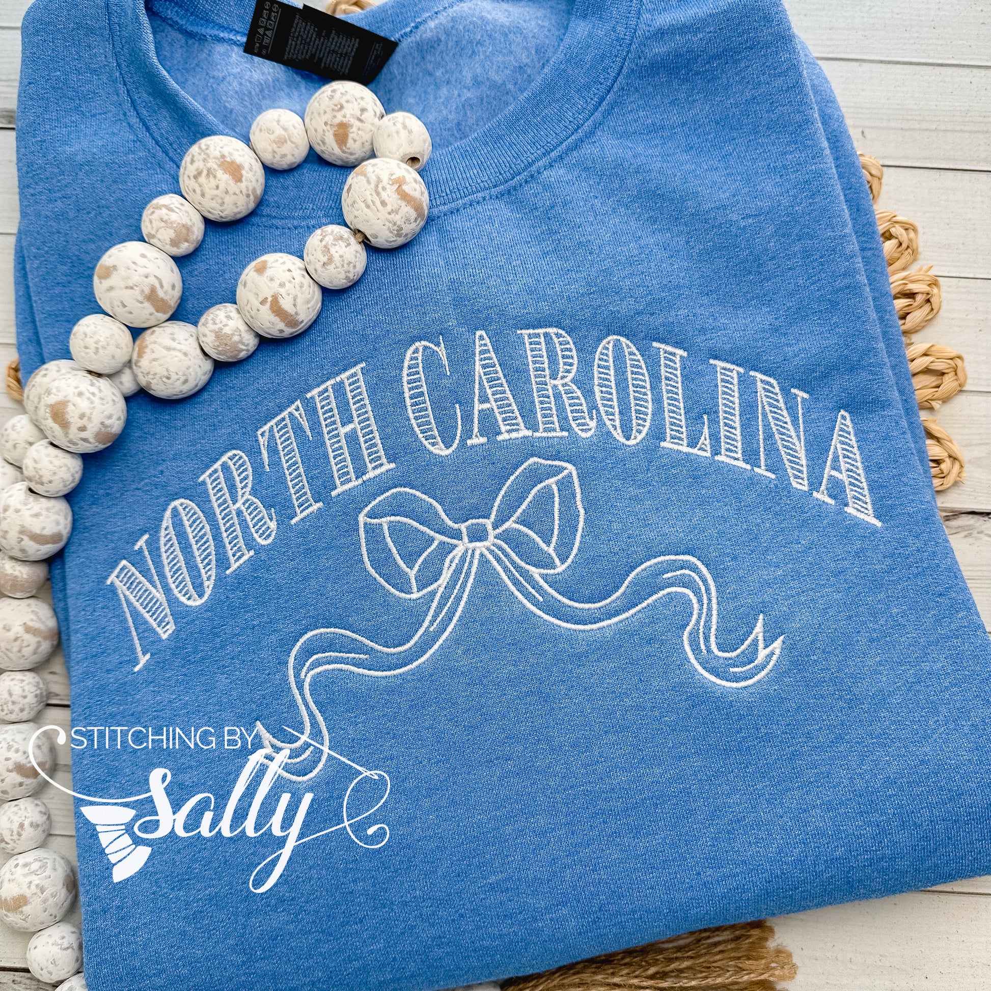 Striped North Carolina embroidered sweatshirt with a coquette bow, available in custom sweatshirt and thread colors. This one is blue