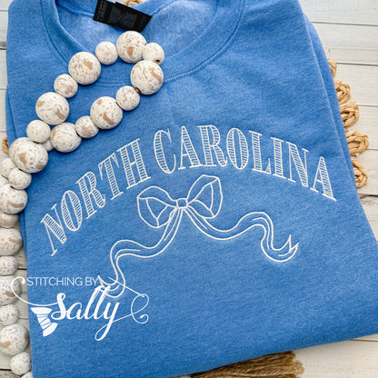 Striped North Carolina embroidered sweatshirt with a coquette bow, available in custom sweatshirt and thread colors. This one is blue
