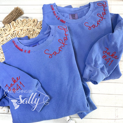 Hand-distressed embroidered crewneck with personalized team name around neckline and players name and number on sleeve