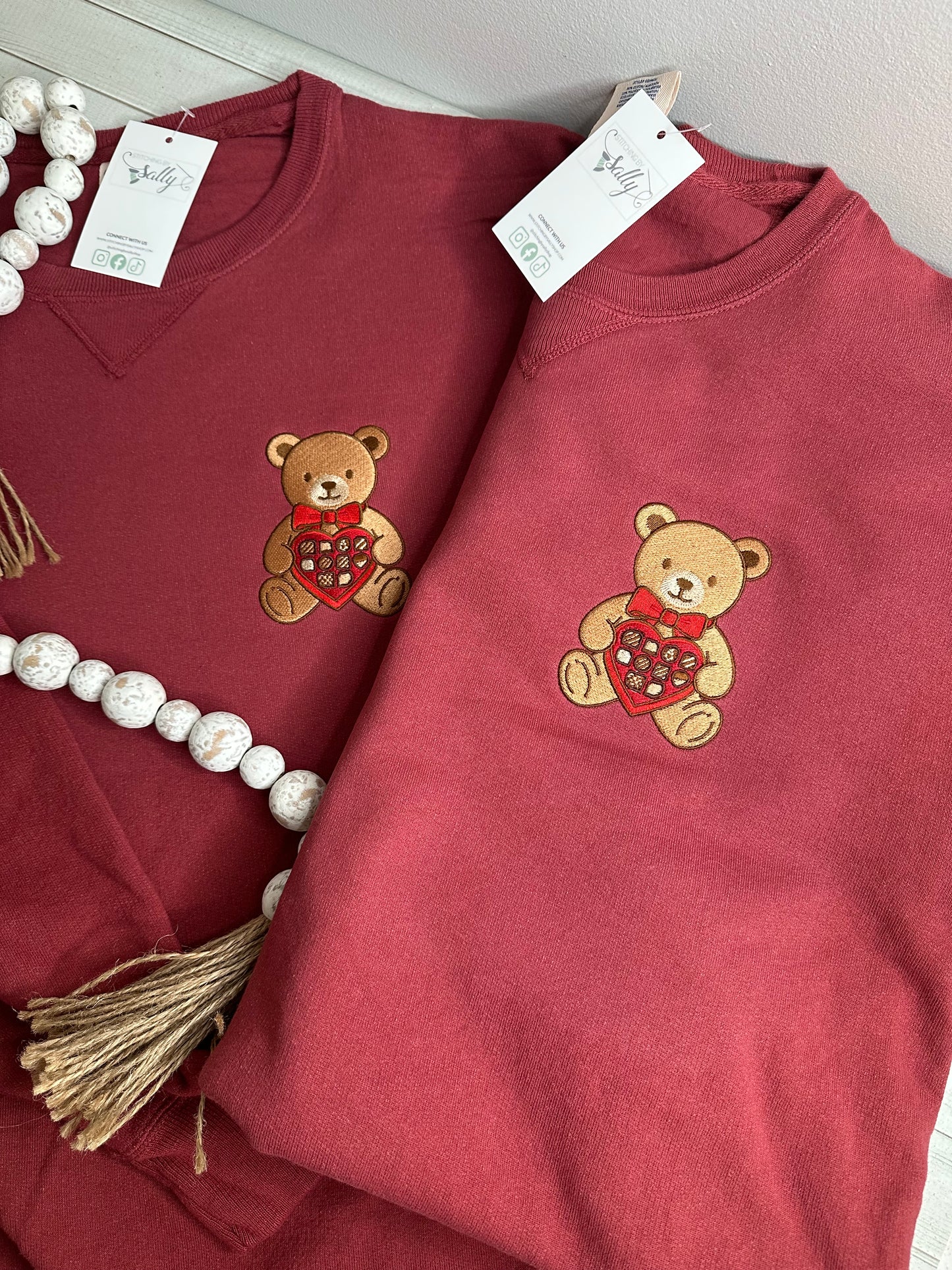 A bear with a box of chocolates embroidered onto a sweatshirt