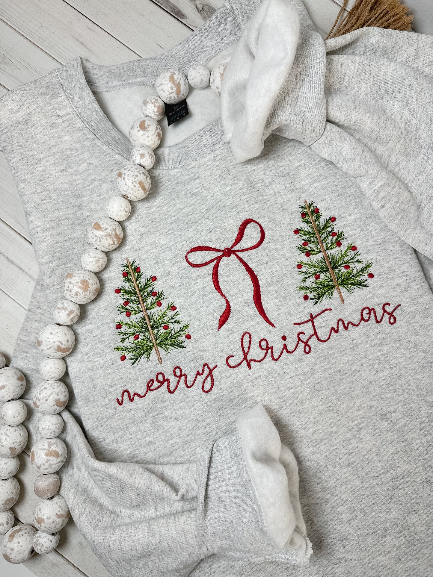 Gray sweatshirt with Christmas design featuring trees and a bow embroidered.