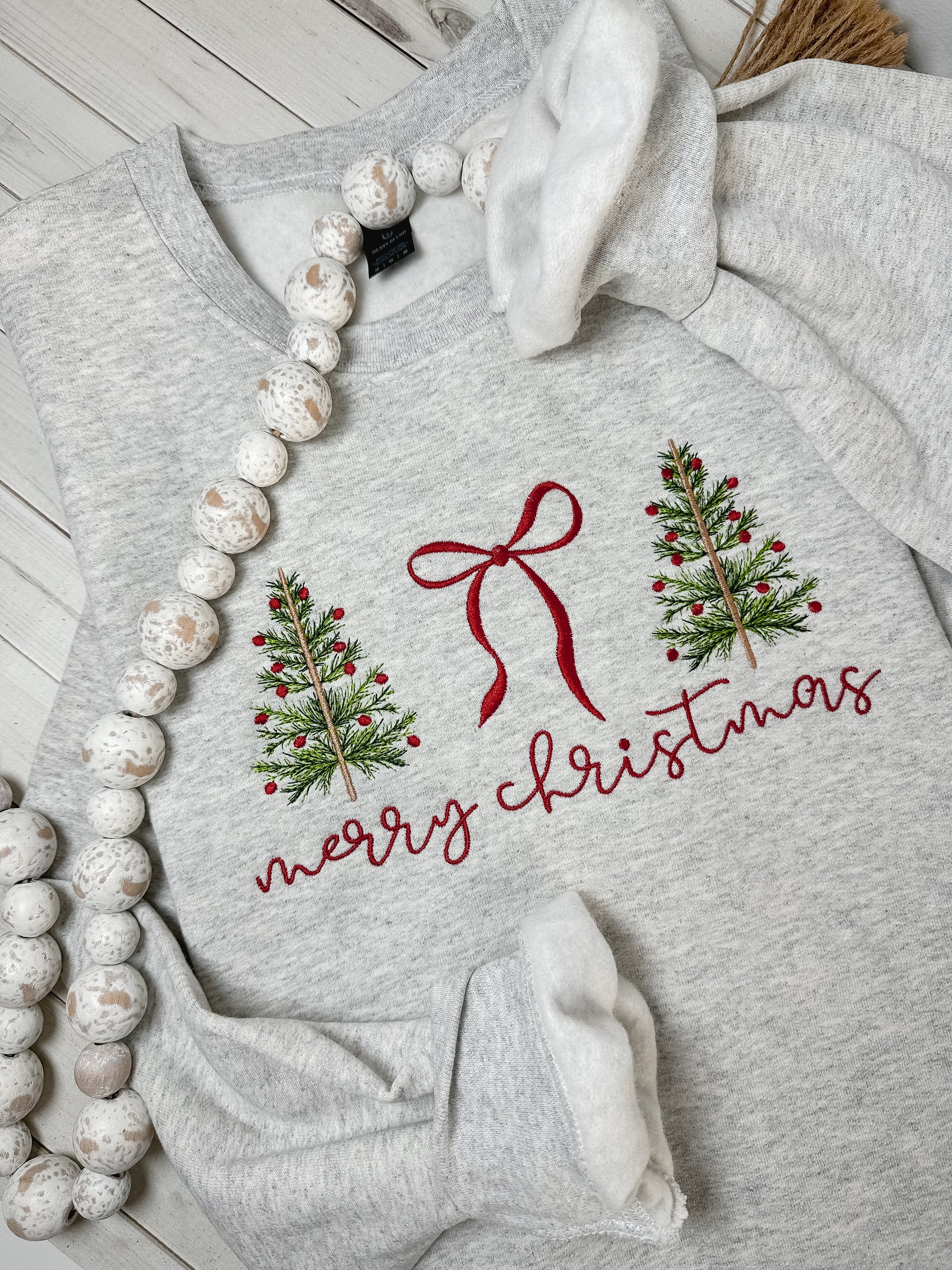 Gray sweatshirt with Christmas design featuring trees and a bow embroidered.