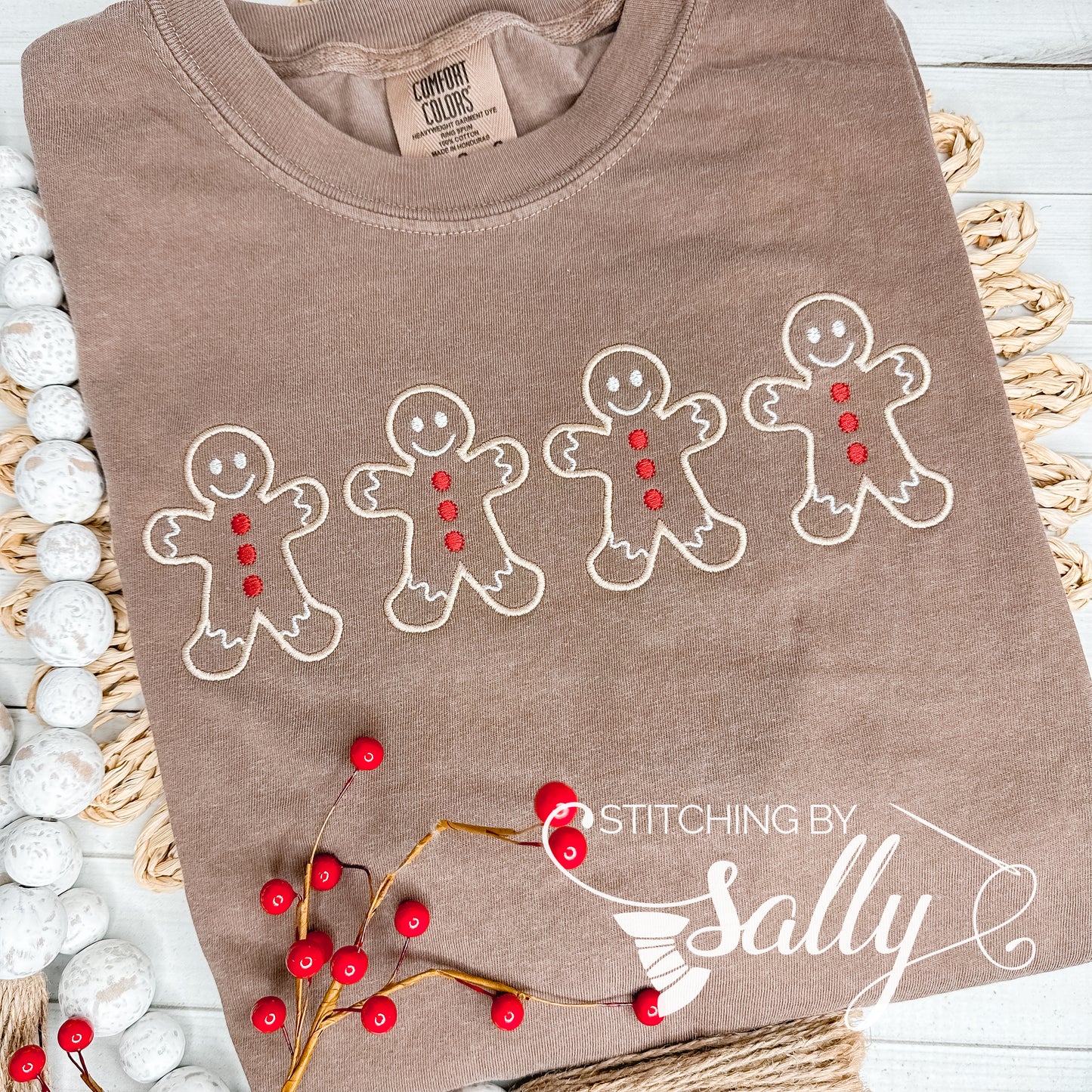 A brown shirt with four Gingerbread men embroidered in tan thread with red buttons. 
