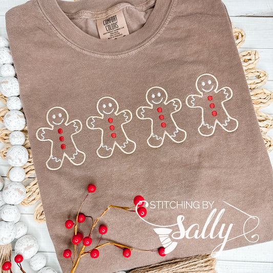 A brown shirt with four Gingerbread men embroidered in tan thread with red buttons. 