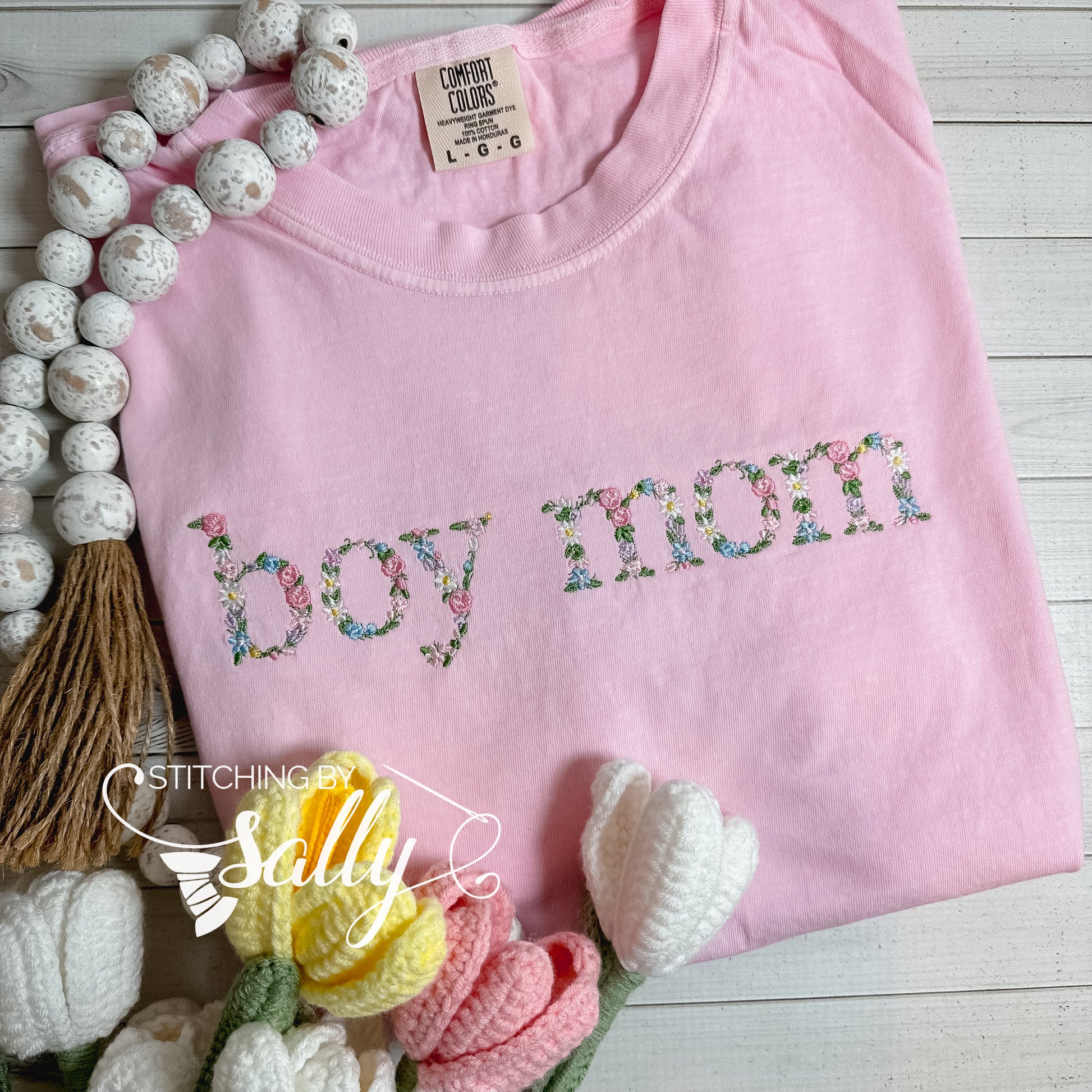 Boy mom embroidered in a delicate floral design on a pink shirt.