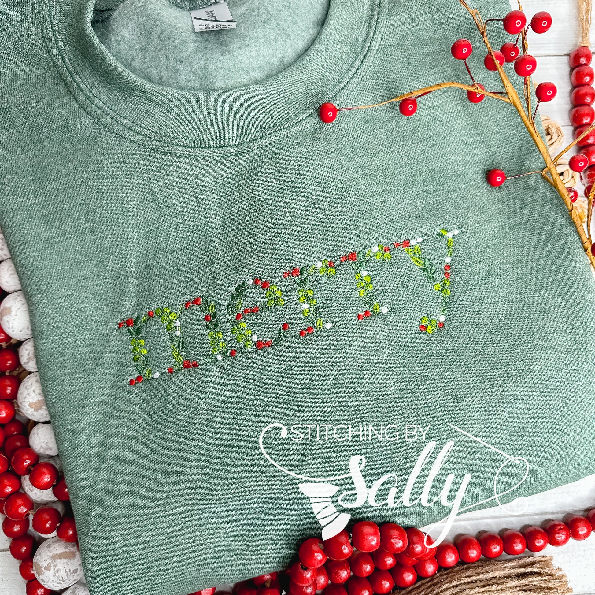 Green sweatshirt with "merry" embroidered in festive leaves and berries font, perfect for adding a touch of cheer to your wardrobe. 