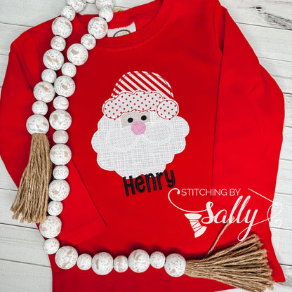 Red shirt with Santa Claus design and 'Henry' text, decorated with beads and tassels on a wooden surface.