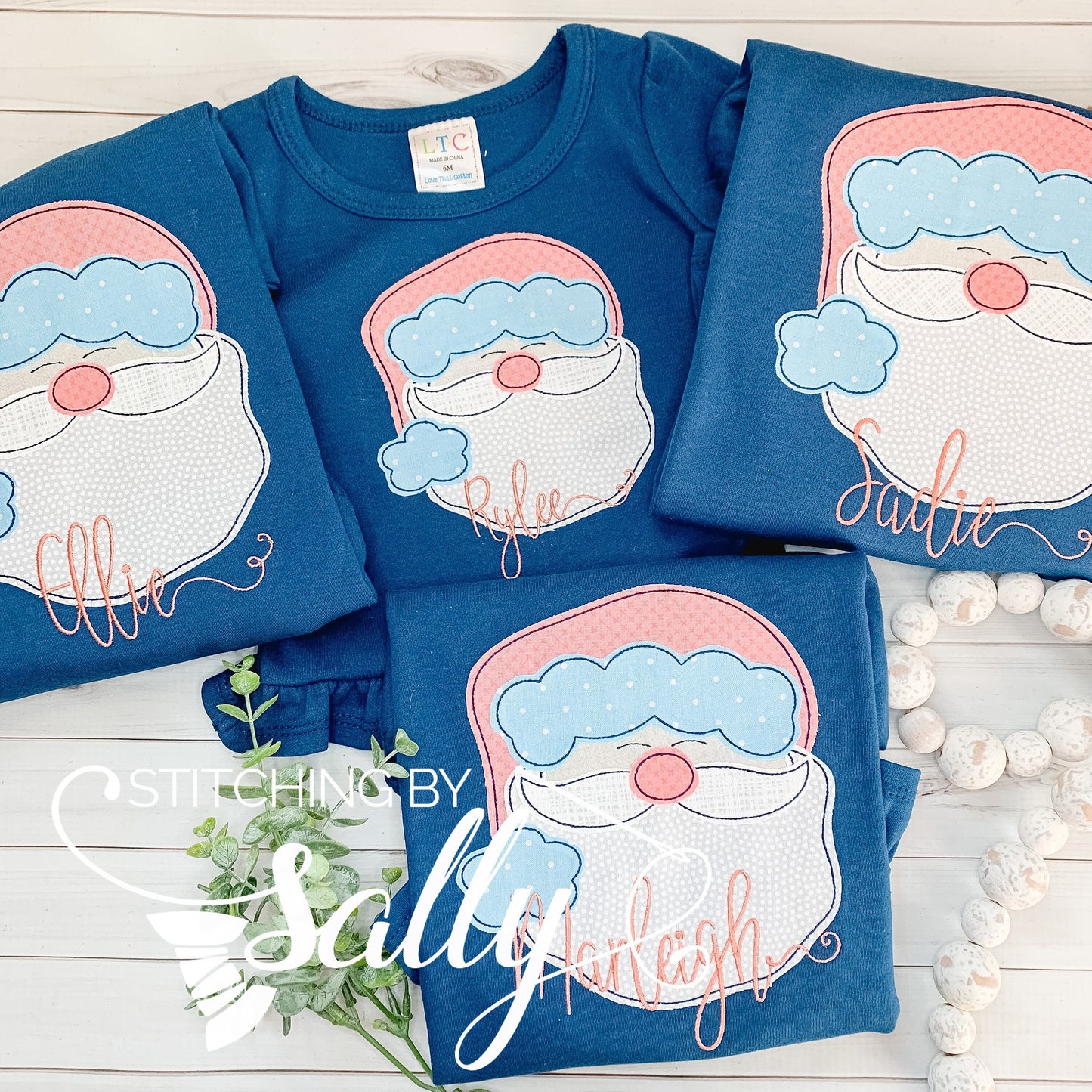 Four navy shirts with a santa face appliquéd using pink fabric for the hat.
