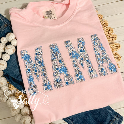 Light pink Comfort Colors shirt featuring 'Mama' appliqué in a beautiful blue and pink floral fabric, finished with a delicate diamond stitch in light pink thread for a soft, elegant touch. Perfect for mothers day.