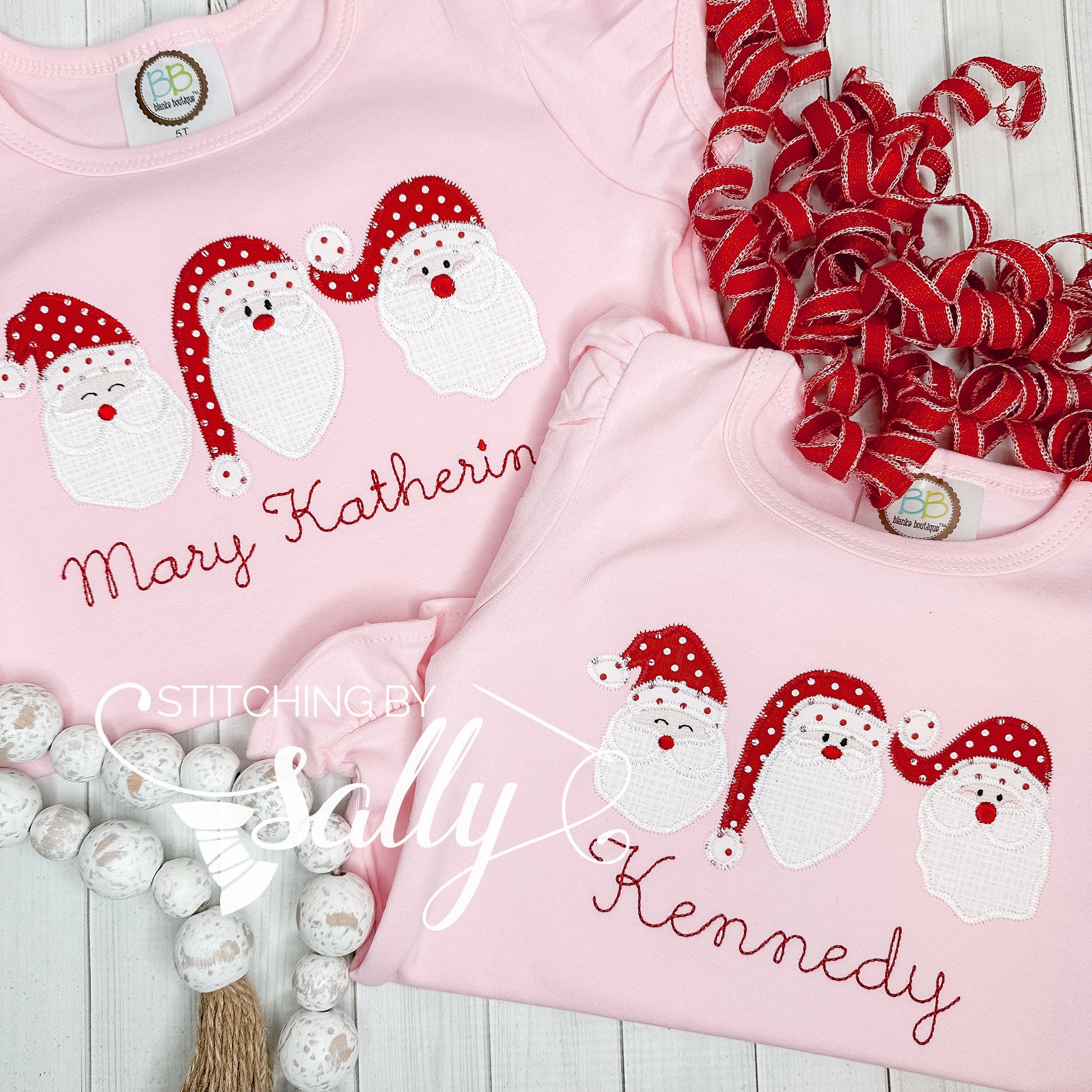 Two pink shirts with embroidered Santa Claus and personalized text names, surrounded by red and white decorations.