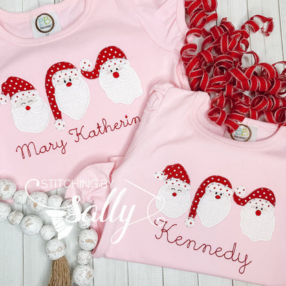 Two pink shirts with embroidered Santa Claus and personalized text names, surrounded by red and white decorations.
