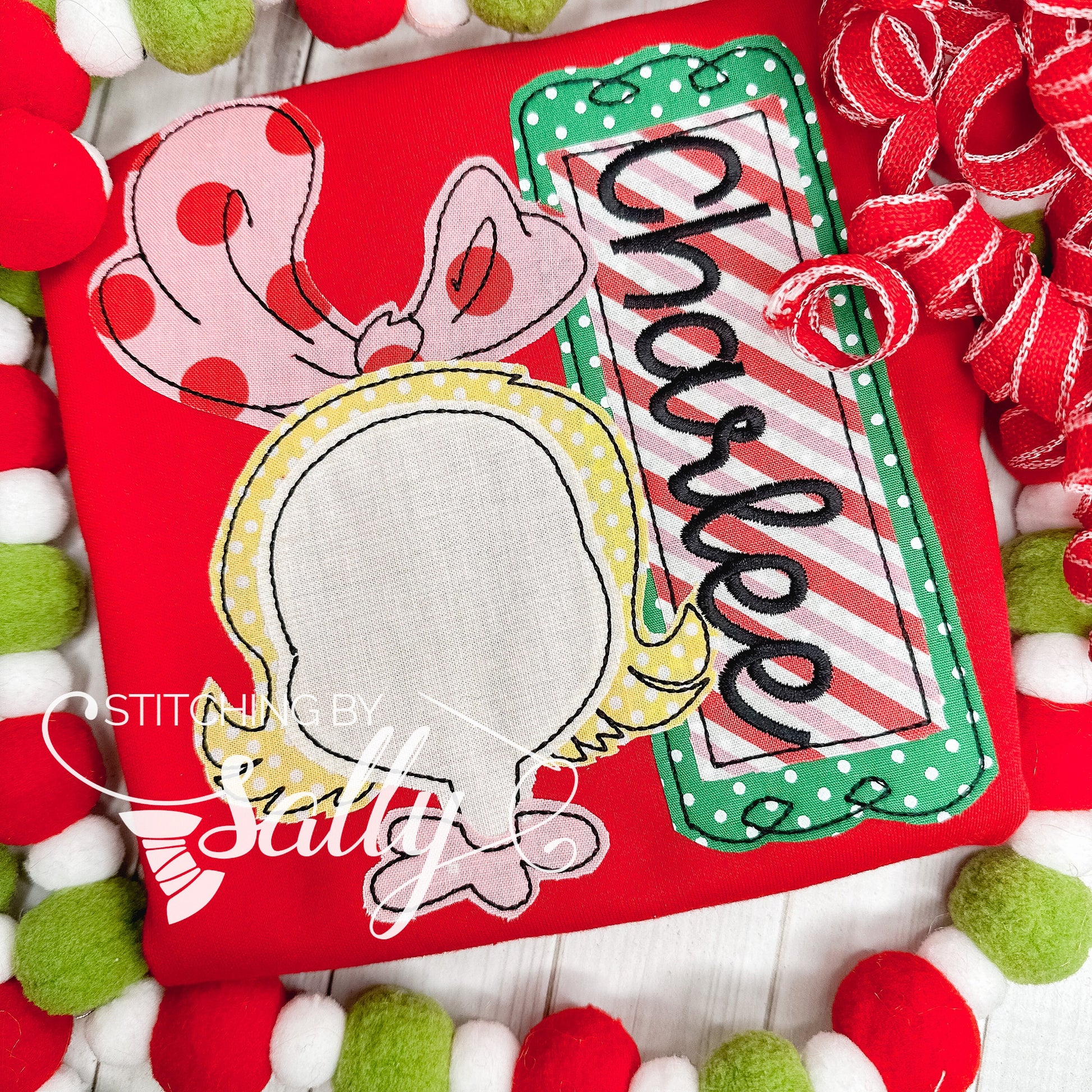 A red shirt with an inspired Cindy Lou drawing appliquéd with festive red, green and pink fabric. 