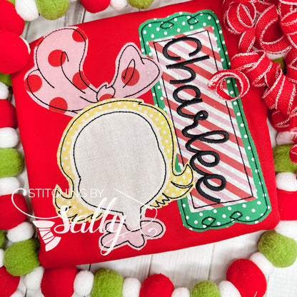 A red shirt with an inspired Cindy Lou drawing appliquéd with festive red, green and pink fabric. 