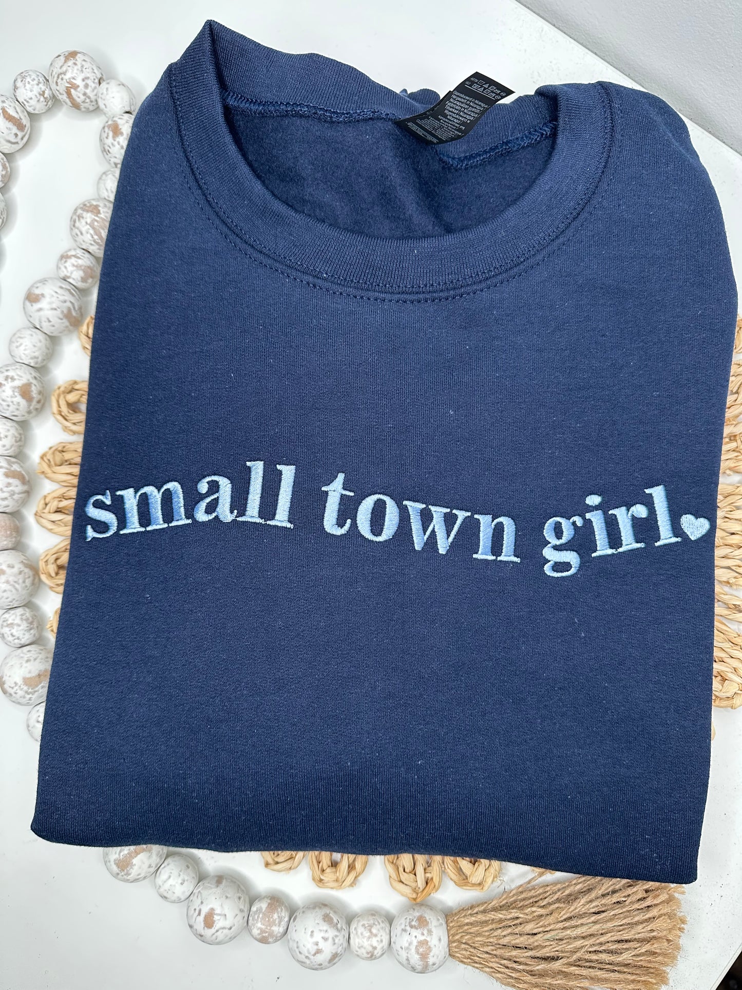 Navy blue sweatshirt with 'small town girl' embroidered in light blue thread. 